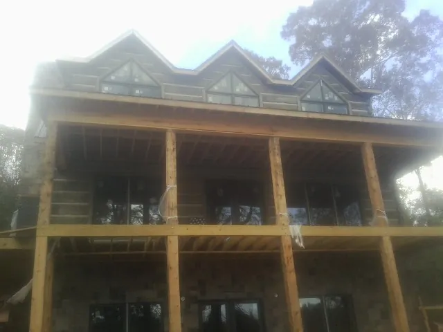 Dormers and porch framing on a large log home under construction — Roof Coating work by our crew in Somers